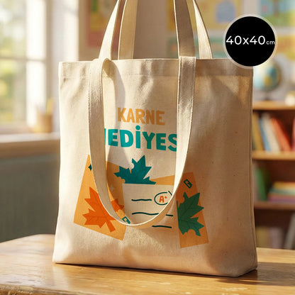 Rengarenk bir sınıf ortamında, ahşap masada sergilenen 40x40 cm çift kulplu ham pamuk bez çanta, 38 cm kısa ve 70 cm uzun saplı.