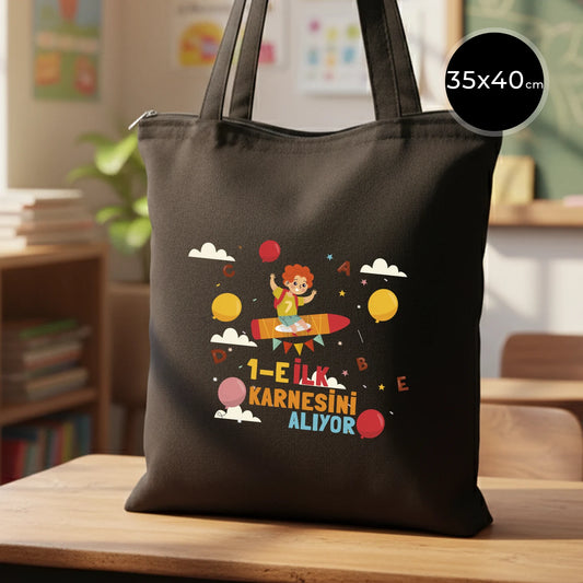 Renkli ve sıcak bir sınıf ortamında, ahşap masada sergilenen 35x40 cm siyah gabardin fermuarlı çanta, 70 cm saplı.