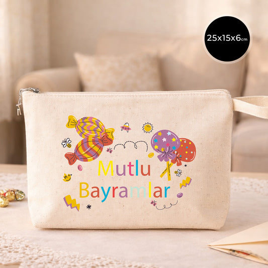 25×15×6 cm ölçülerinde doğal ham bez fermuarlı çanta üzerinde renkli şeker ve lolipop illüstrasyonlarıyla “Mutlu Bayramlar” yazısı; arka planda açık renkli kanepe.