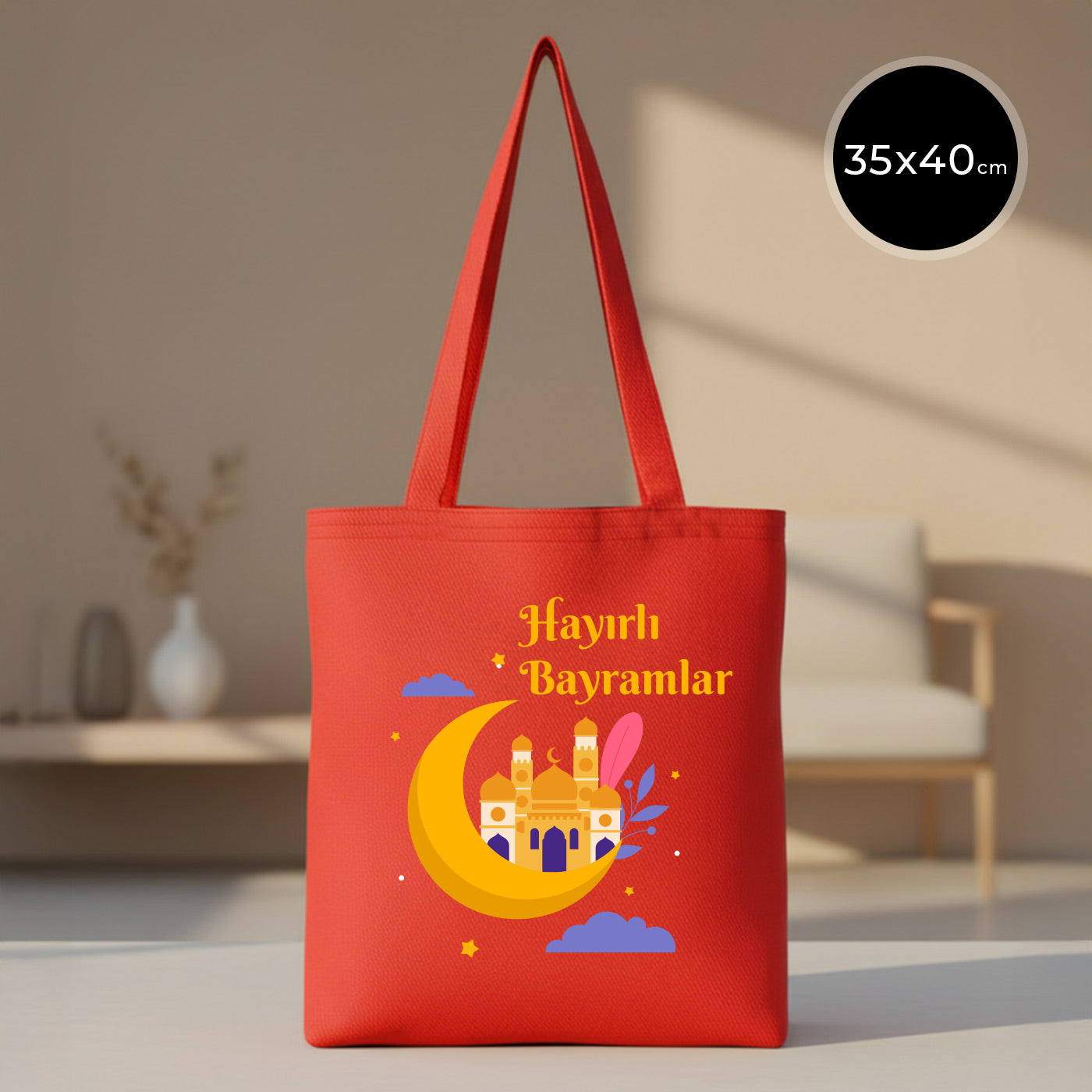 35×40 cm ölçülerinde kırmızı gabardin bez tote çanta üzerinde sarı hilal içinde cami illüstrasyonu, mor bulutlar ve yıldız detaylarıyla birlikte üstte “Hayırlı Bayramlar” yazısı; kırmızı omuz askıları ve sade açık renkli arka plan.